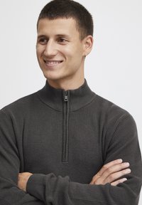 Pull en maille côtelée gris foncé avec col montant et fermeture zip demi-longueur. Fabriqué en tissu texturé, il présente des manches longues et une coupe ajustée.
