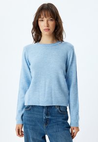 Helles blaues Sweatshirt, lange Ärmel, gerippter Halsausschnitt und Saum, weiche Textur, lockere Passform, kombiniert mit blauen Jeans, minimalistisches Design.