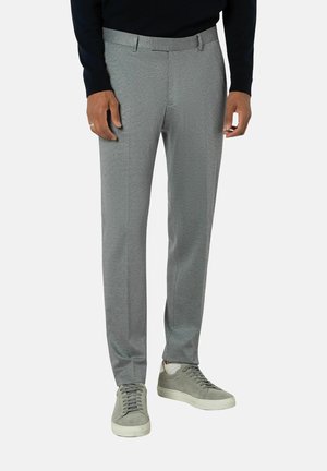Graue maßgeschneiderte Hosen mit strukturiertem Finish, ausgestattet mit einem Standardbund und seitlichen Taschen, kombiniert mit hellgrauen Sneakers.