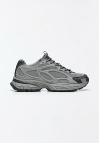 Baskets de sport grises avec accents noirs, panneaux en mesh et semelle épaisse, vues de côté sur fond blanc.