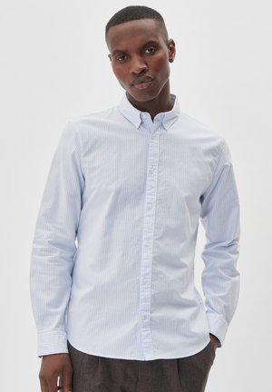 Camisa abotonada de rayas azules claras y blancas con cuello, de mangas largas y dobladillo redondeado. La textura de la tela parece suave y nítida.