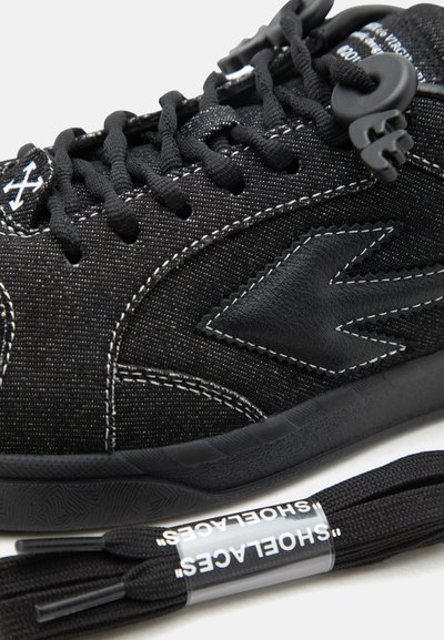 Μαύρο αθλητικό παπούτσι με υφασμάτινη υφή και δερμάτινες λεπτομέρειες, παχύ μαύρο πέλμα, μαύρα κορδόνια και επιπλέον ζευγάρι μαύρα κορδόνια με την ετικέτα "SHOELACES".