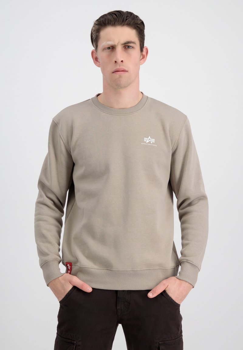Beige mikina z měkké tkaniny, s kulatým výstřihem, s žebrovanými manžetami a lemem. Na hrudi má bílé logo a na boku červenou visačku.