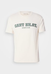 Cream cotton t-shirt featuring a round neckline and short sleeves. The front displays "GANT NH. CT." and "SPORTS CLUB" in green and black text.