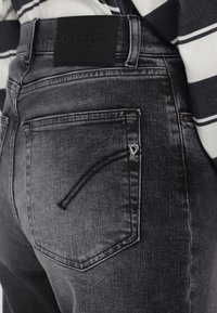 Jeans in denim nero con vestibilità slim, caratterizzati da un design distintivo delle tasche, un leggero effetto lavatore e un'etichetta testurizzata sulla vita.