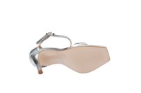 Sandal con tacón metálico plateado, con tiras al tobillo, punta abierta y suela texturizada. Presenta un tacón cuadrado modesto y un diseño elegante y minimalista.