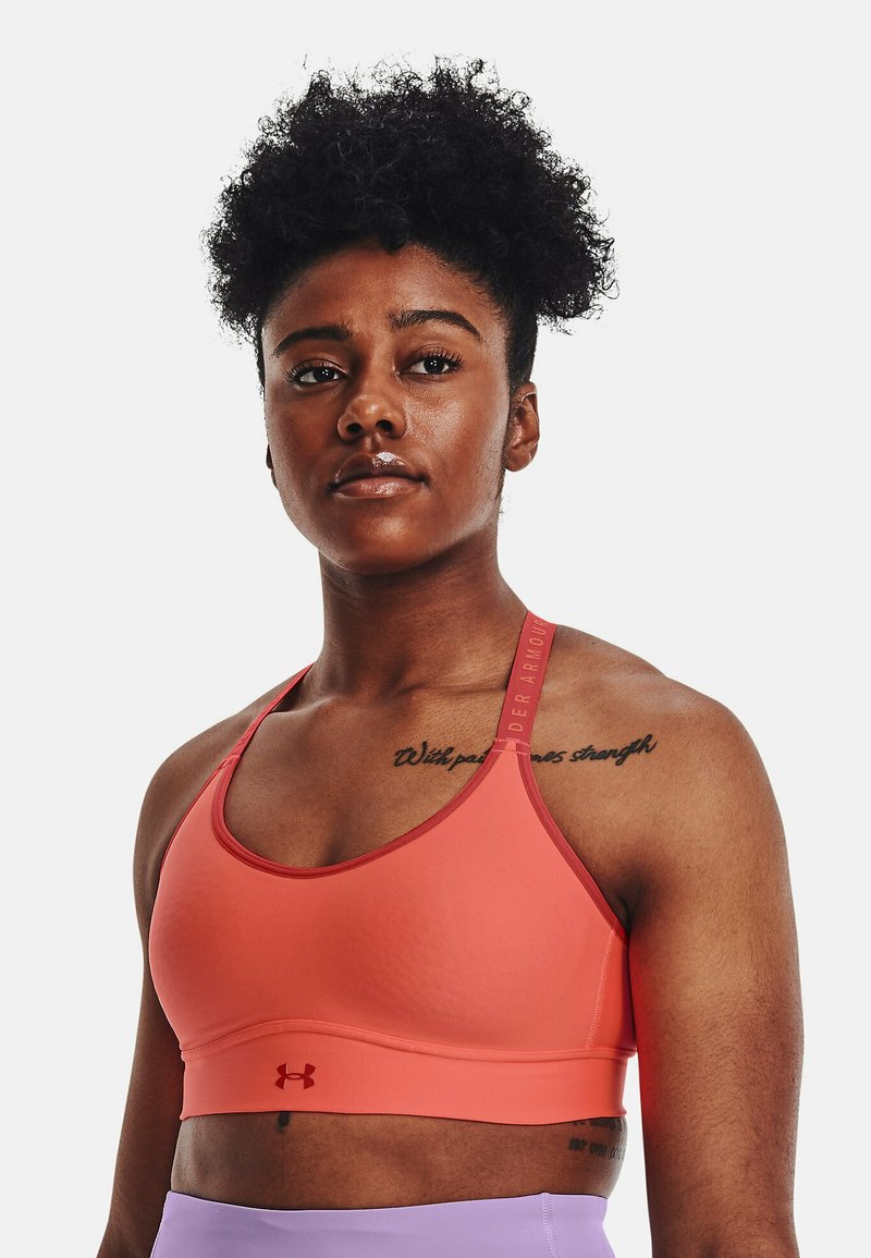 Koraļa sporta krūšturis ar gludu tekstūru, platām siksnām ar logotipu un pieguļošu dizainu. Akcentēts ar zemu izgriezumu un elastīgu jostu.