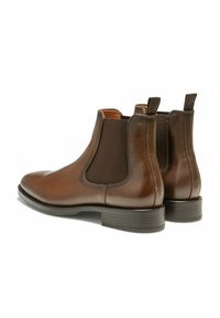 Bottines Chelsea en cuir marron avec des panneaux latéraux élastiques, des bouts ronds et une semelle en caoutchouc plate. Comprend des petites languettes pour un enfilage facile.