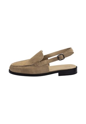 Mocassin slingback beige en suède avec bride à boucle noire, bout cousu, semelle plate noire et petit talon.