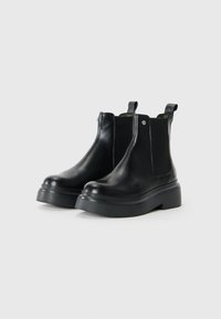 Black leather chelsea boots with elastic side panels, sturdy ankle height, and thick platform sole. Includes pull tabs for easy wear.