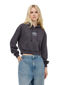 Przycięta ciemnoszara bluza z kapturem regulowanym sznurkiem i białą grafiką "Flower Shop". W zestawie z wysokim stanem jasnoniebieskie dżinsy.