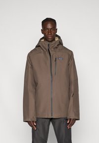 Giacca impermeabile marrone con cappuccio, zip frontale e tasche laterali. Progettata con una trama liscia e una vestibilità ampia per il massimo comfort.