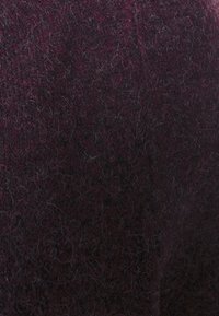 Tessuto texturizzato in un profondo bordeaux con sottili fibre chiare sparse, che mette in risalto un aspetto morbido simile alla lana e una trama intricata.