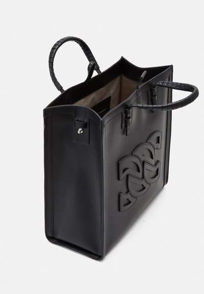 Sac fourre-tout en cuir noir au design structuré, avec deux poignées et un détail de logo en relief sur le devant, l'intérieur est doublé d'un tissu clair.