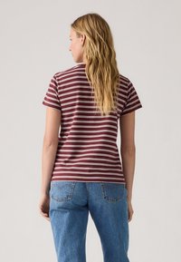 T-shirt rayé bordeaux à manches courtes, en coton, avec une coupe décontractée, associé à un jean en denim bleu taille haute.