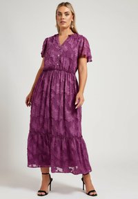 Lila maxiklänning i genomskinligt tyg, med ett blommönster, knäppt v-ringning, volangärmar och elastisk midja.