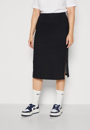 Falda midi a rayas negras con una abertura lateral, hecha de tela texturizada. Combinada con calcetines y zapatillas Nike blancas.