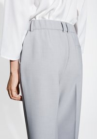 Graue maßgeschneiderte Hose mit glatter Textur, hoch geschnittenem Bund, Gürtelschlaufen und Gesäßtaschen. Der Stoff hat einen subtilen Glanz.