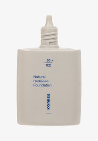 Biała prostokątna butelka z zakrętką, oznaczona napisem „Natural Radiance Foundation” w niebieskim kolorze, z zaokrąglonym wierzchem i teksturowaną powierzchnią.