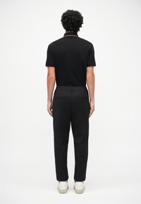 Pachet polo negru cu mâneci scurte, având o margine albă a gulerului, asortat cu pantaloni negri și adidași albi. Design simplu, fără modele vizibile.
