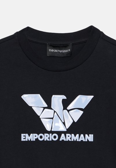 Μαύρο T-shirt με λευκό σπασμένο λογότυπο αετού και κείμενο "EMPORIO ARMANI" κάτω από την ετικέτα του γιακά.
