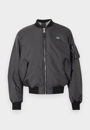 Czarna kurtka typu bomber z przednim zamkiem błyskawicznym, ściągaczami przy mankietach i dolnym brzegu, kieszeniami z patkami oraz zapinaną na zamek kieszenią z brelokiem na lewym rękawie.