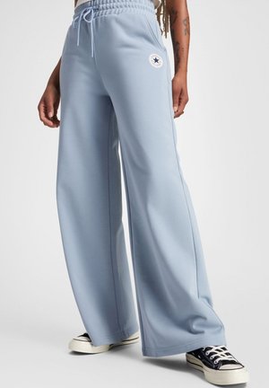 Pantalones de chándal de pernera ancha en azul claro con cinturilla elástica, cordón, bolsillos laterales y un parche con el logo en el muslo izquierdo.