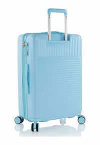 Valigia rigida di colore azzurro chiaro, con scanalature verticali, una maniglia telescopica in alluminio e quattro ruote per la mobilità.