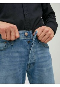 Ljusblå denimjeans med dragkedja och knappstängning, med en lätt blekt yta och diskreta sömnadsdetaljer.
