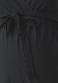 Zwarte wikkeljurk van zachte stof, met een vastgebonden taille en een licht gecentreerd ontwerp voor een ontspannen pasvorm. Glad textuur, minimale details.