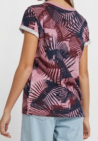 Koszulka z krótkim rękawem, różowa z ciemnoniebieskim i burgundowym nadrukiem palmowych liści, lekka tkanina, okrągły dekolt i podwinięte rękawy.