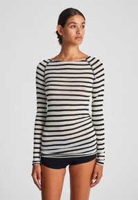 Langarm, aansluitend top van doorzichtig materiaal, met zwart-witte horizontale strepen, een bootnek en contrasterende stiksels.