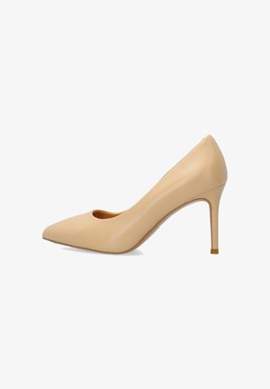 Beige leren pumps met spitse neus en een smalle naaldhak, van opzij gezien tegen een witte achtergrond.