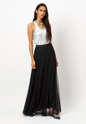 Haut sans manches argenté avec une finition brillante, associé à une longue jupe maxi en tulle noir fluide, dotée d'une taille ajustée et d'une texture superposée.