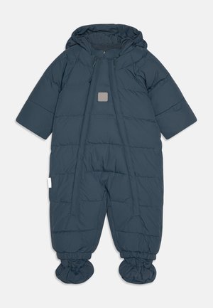 Mørkeblå polstret flyverdragt med hætte, forsynet med lynlås foran og elastiske manchetter. Stoffet har et quiltet mønster og en lille logopatch.