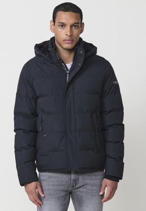 Chaqueta puffer negra con capucha, con un diseño acolchado, bolsillos con cremallera y cordones ajustables. Acabado elegante, material resistente al agua.