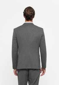 Grau maßgeschneiderte Anzugjacke mit strukturierter Silhouette, mit Reverskragen und subtiler Textur. Einschließlich detaillierter Nähte an den Manschetten.