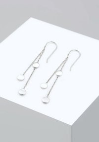 Des boucles d'oreilles en argent présentent deux chaînes avec trois accents circulaires, une finition polie et un design en forme de crochet.