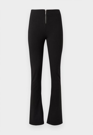 Pantalon noir taille haute, coupe slim, avec une fermeture éclair argentée à l'avant et des bas légèrement évasés, sur fond blanc.