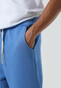 Blauwe katoenen joggingbroek met taps toelopend ontwerp, elastische tailleband, trekkoord en zijzakken, met een zachte, gestructureerde oppervlakte.