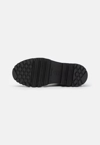 Black rubber outsole with a tread pattern, featuring grooves and ridges for grip. Sturdy construction with a smooth surface and embossed logo.