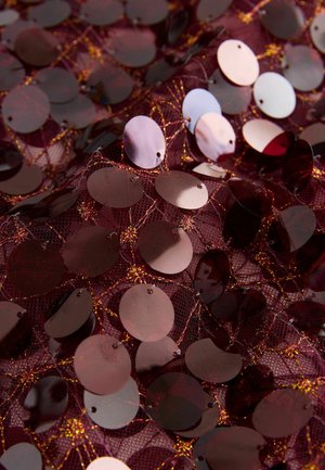 Burgunderfarbener Mesh-Stoff, verziert mit runden Pailletten in dunklen Rot- und Irisierendes Tönen, verbunden durch goldene Fäden. Strukturiert und reflektierend.