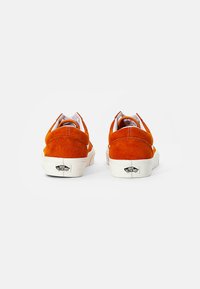 Orange ruskinds sneakers med hvide gummisåler, afrundede bagsider og logodetalje på hælen. Enkel, lavtop design med polstret krave.