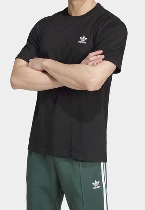 T-shirt en coton noir à manches courtes et col rond. Présente un petit logo Adidas blanc sur la poitrine gauche.