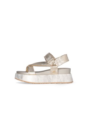 Sandalia de plataforma metálica dorada con correas acolchadas y cierre de velcro, con suela blanca texturizada y diseño de punta abierta.