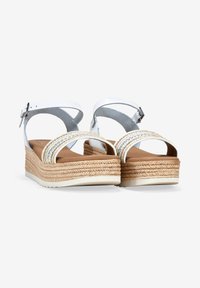 Sandalias de plataforma blancas con dos correas trenzadas, plantilla de yute tejido y suela de goma plana. Correa de tobillo ajustable con hebilla de metal.
