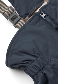 Das dunkelblaue Außenmaterial verfügt über eine Reißverschlusstasche, einen verstellbaren Riemen mit Karomuster und geraffte Details entlang der Nähte.