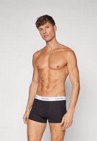 Zwarte katoenen boxershorts met een witte elastische tailleband met het Calvin Klein-logo. Glad textuur, aansluitend ontwerp, minimale details.