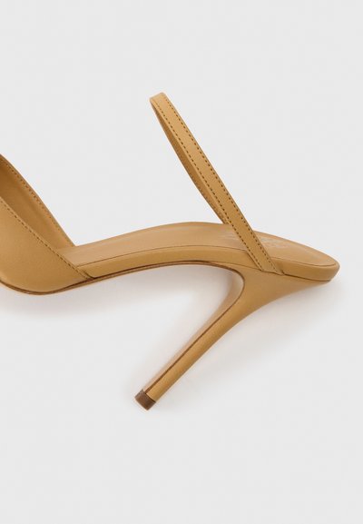 Široká kožená sandál s otevřenou špičkou a tenkým páskem přes nohu na bílém pozadí.