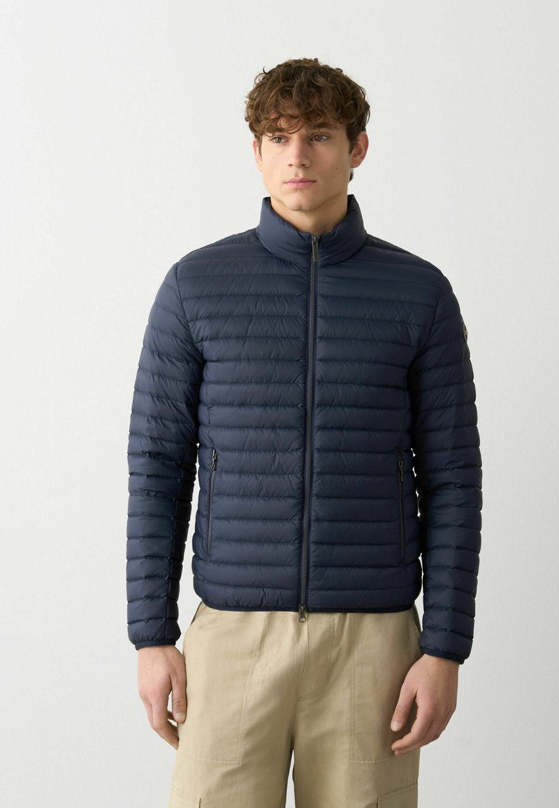 Veste en duvet marine avec des coutures horizontales, un col haut et deux poches latérales zippées. Fabriquée en matériau léger et résistant à l'eau.